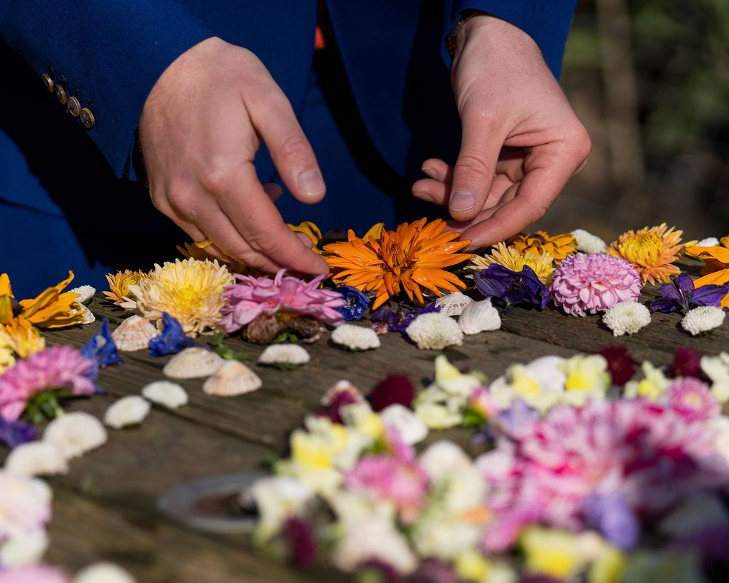 A person's hands placing a flower head in a participative flower mandala ritual