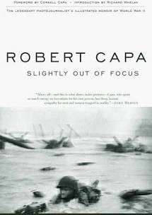 Black and white book cover. The lower half of the cover is an out of focus image of a soldier prone in the surf amidst obstacles during the D-Day invasion. Across the upper portion of the cover in bold capital letters is ROBERT CAPA, below which is the title of the book “SLIGHTLY OUT OF FOCUS.”