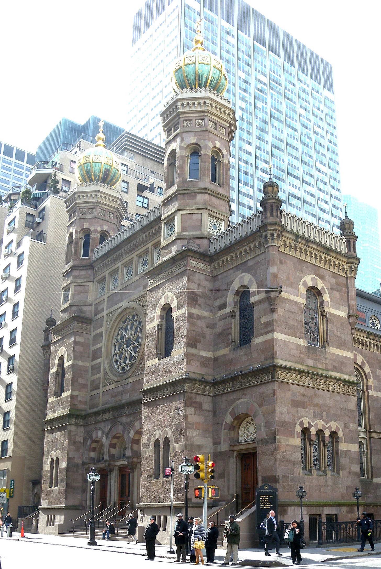 Central Synagogue’s two domed towers and stone façade above pedestrians crossing Lexington Avenue.
