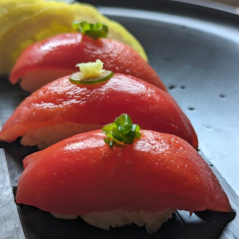 Three plated tomato tuna dishes: Tomato Tuna Nigiri, Tomato Tuna and Mango Tartare, and Tomato Tuna Sashimi drizzled with ponzu butter and garnished with crispy potato shreds..