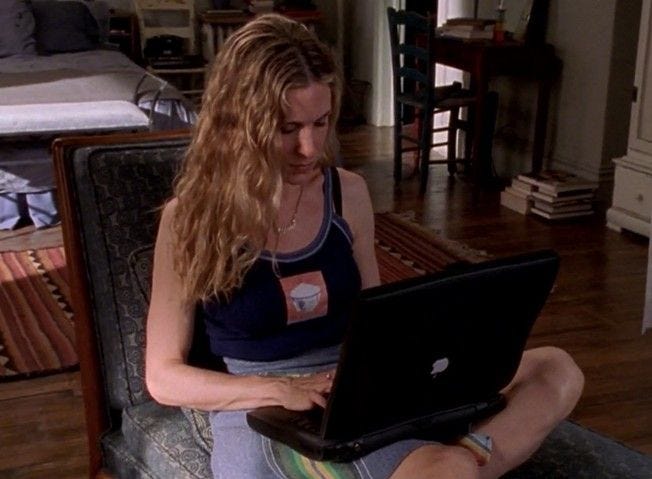 This may contain: a woman sitting on the floor using a laptop computer