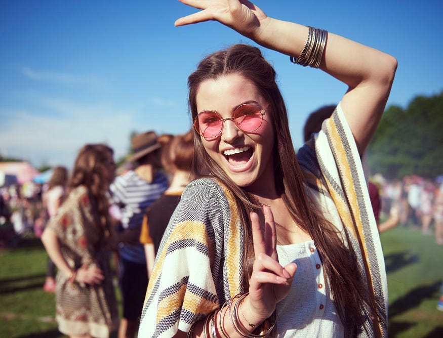 Young woman in pink sunglasses poses for the camera at a music festival Young woman in pink sunglasses poses for the camera at a music festival