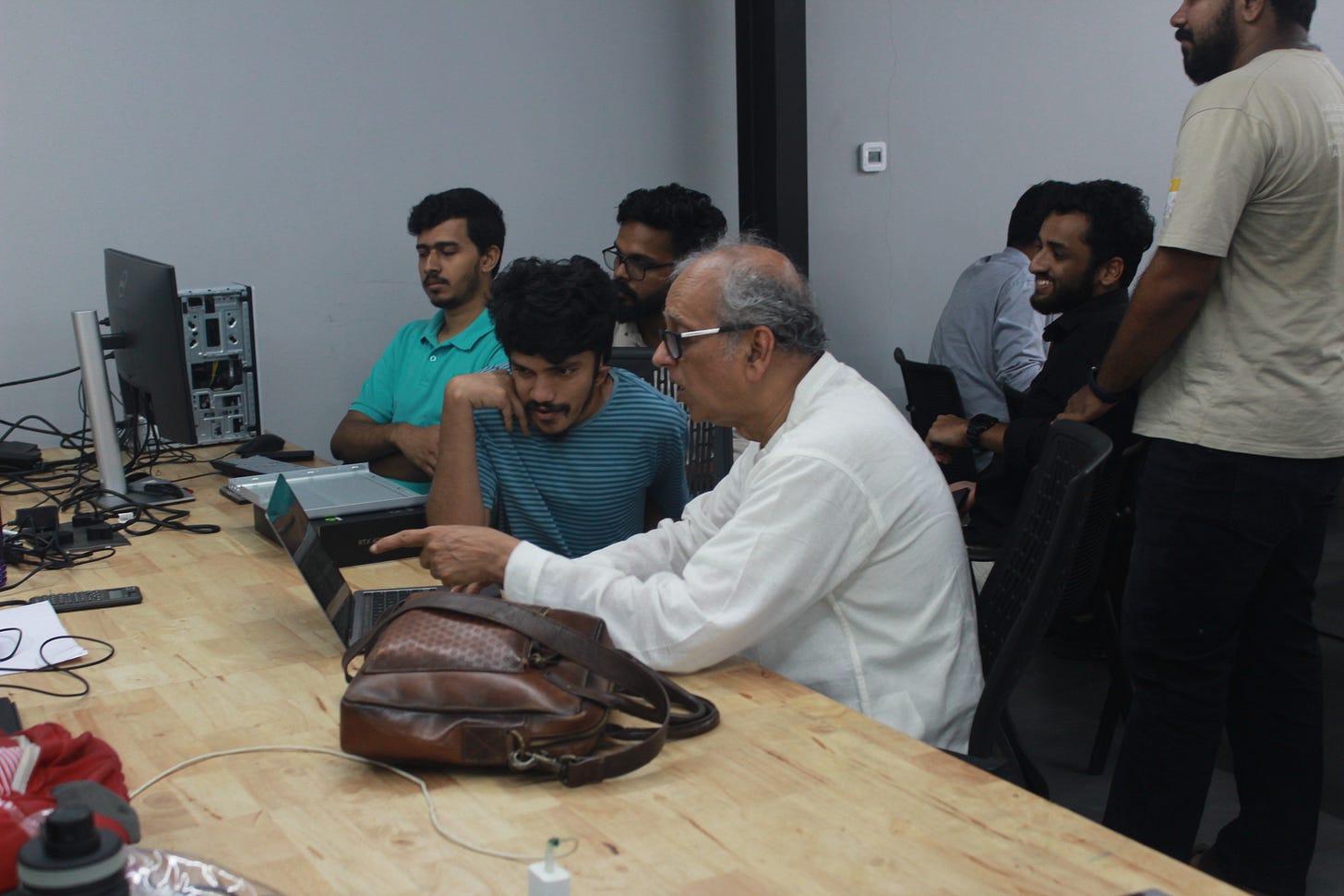A group of people sitting around a table with laptops A group of people sitting around a table with laptops