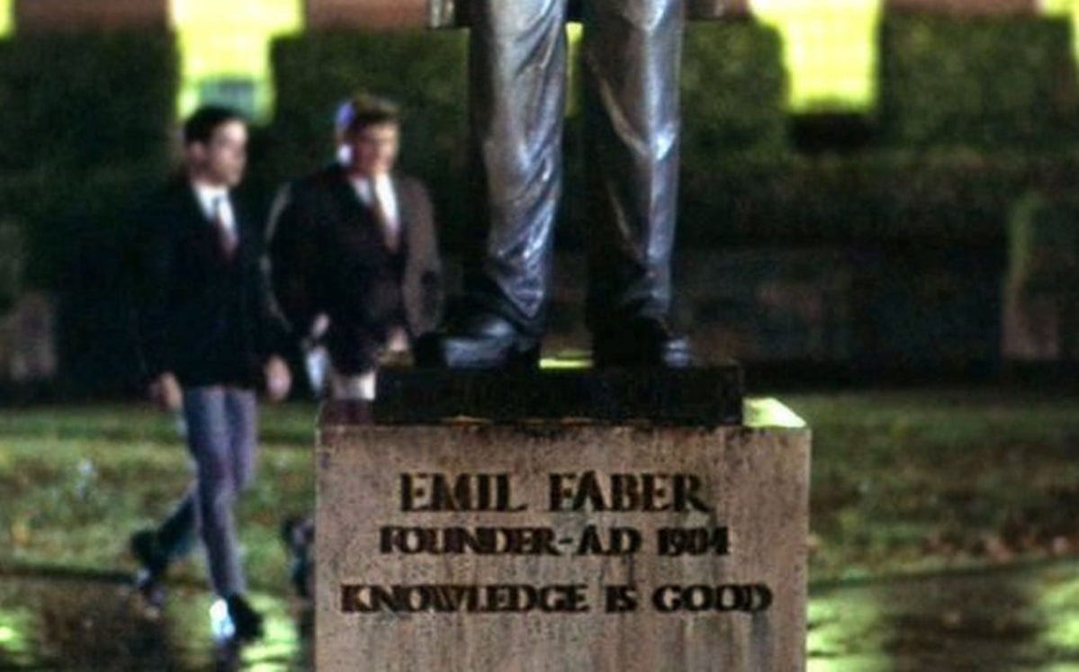 Still from Animal House, showing the statue of Faber College (or his legs at least) on a pedestal with the inscription 'Emil Faber, Founder _ AD 1904.' and the motto 'Knowledge is Good'