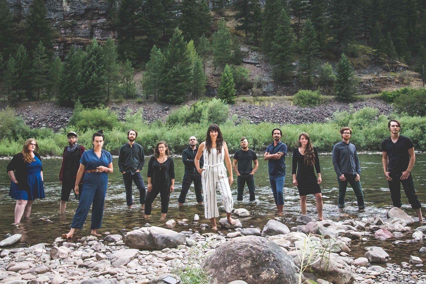band in blue with sarah in center in white on bank of stream
