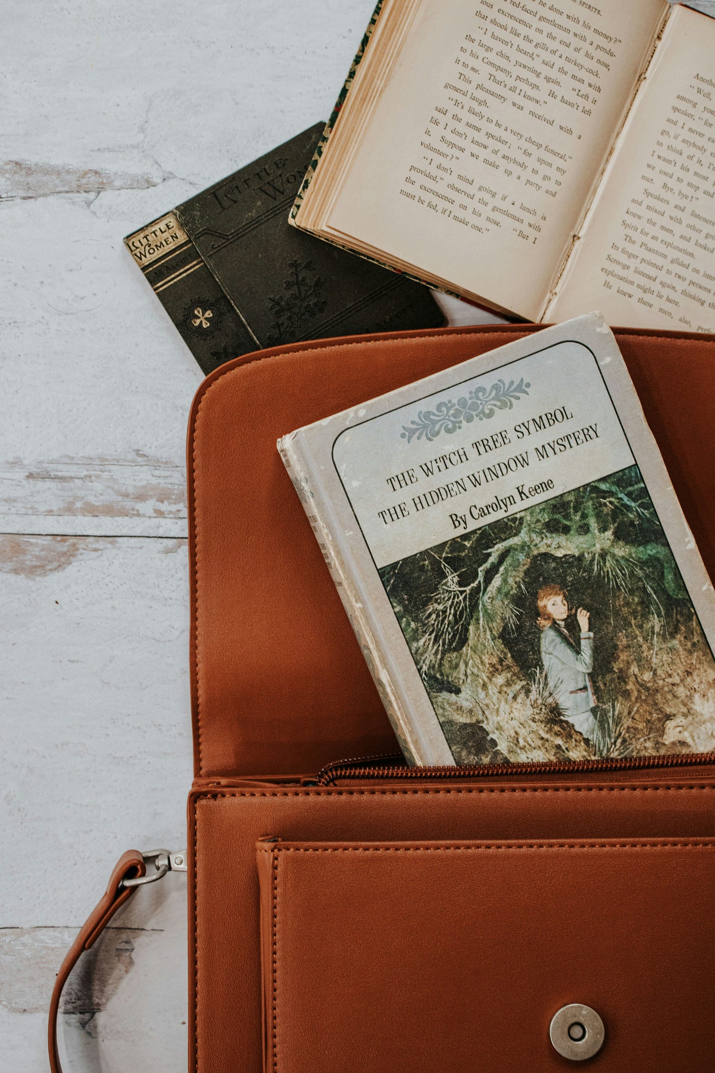 brown leather crossbody with Nancy Drew book peeking out, as a "clue"
