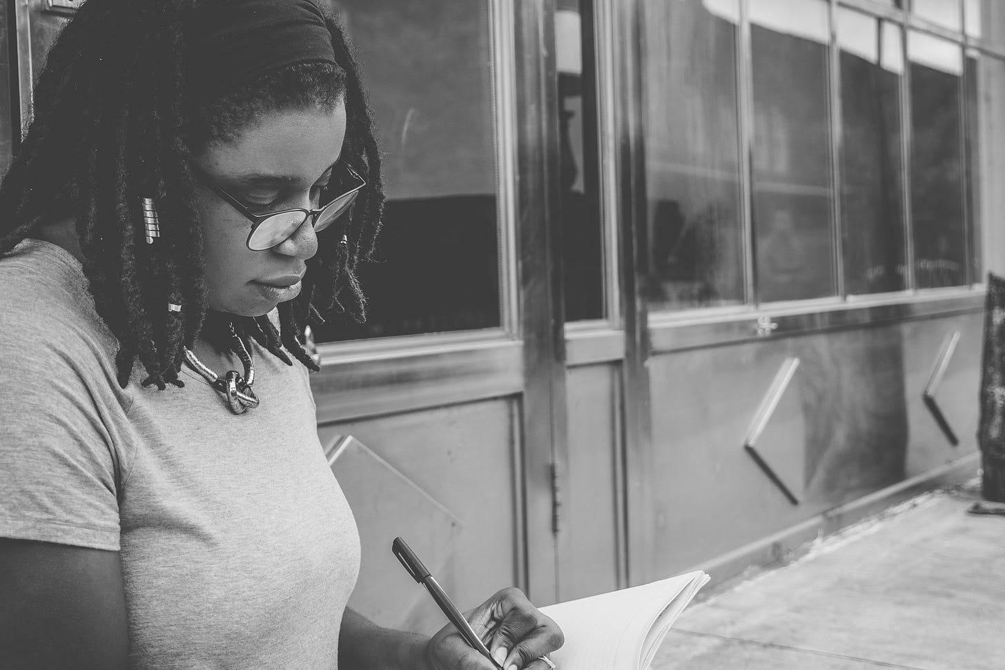 African American young lady writing in a notebook while sitting on a bench African American young lady writing in a notebook while sitting on a bench