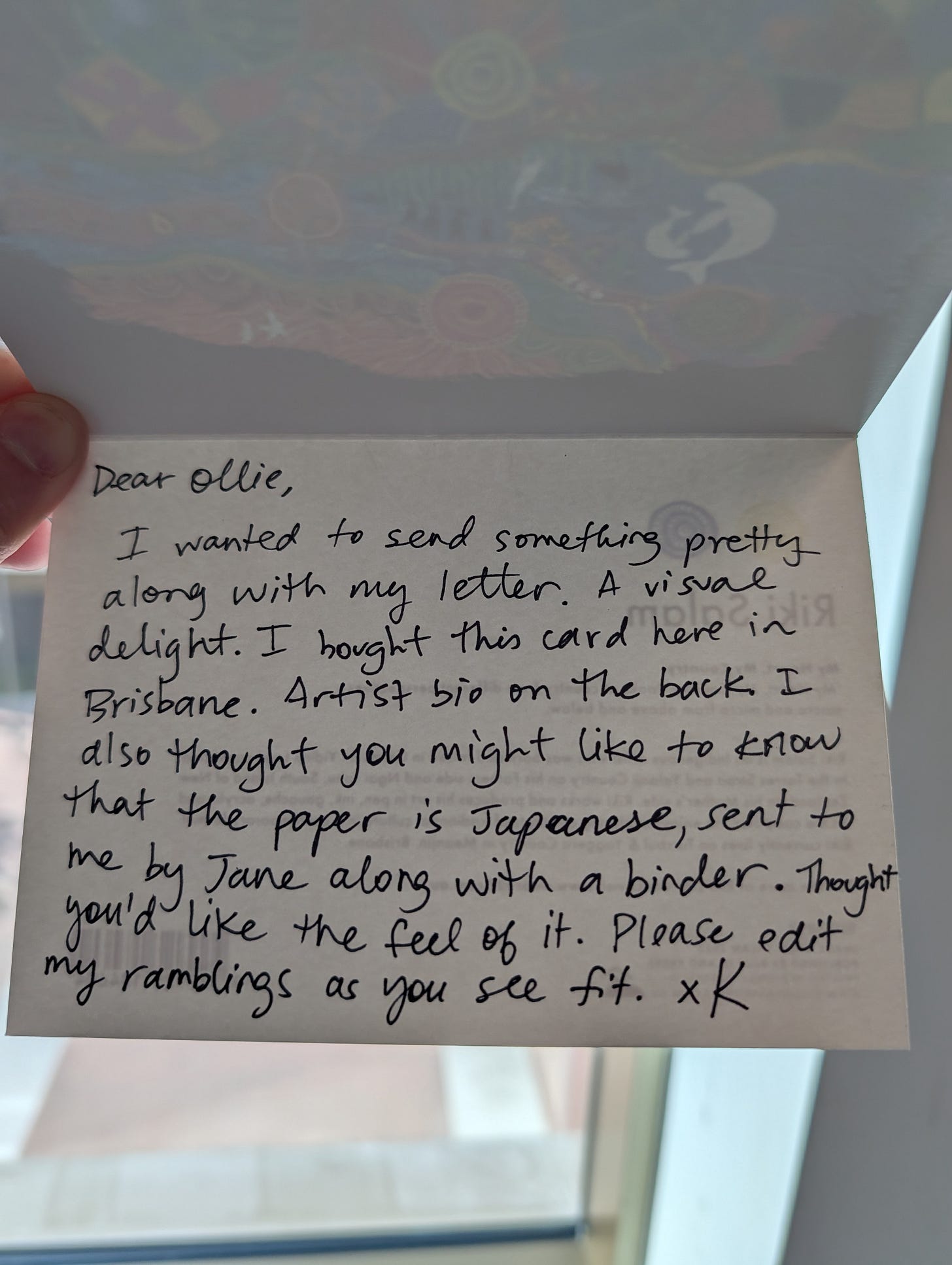 Handwritten note on cream cardstock reading "Dear Ollie" followed by text explaining the card is a visual gift purchased in Brisbane on Japanese paper, with artist bio on the back. A note asks you to edit the author's ramblings. Signed "x K."
