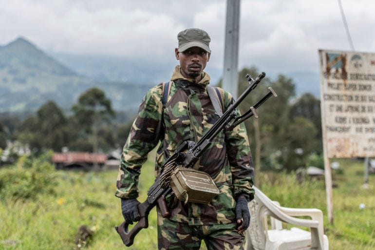 A M23 rebel stands with his weapon during a ceremony to mark the withdrawal from their positions in the town of Kibumba. A M23 rebel stands with his weapon during a ceremony to mark the withdrawal from their positions in the town of Kibumba.