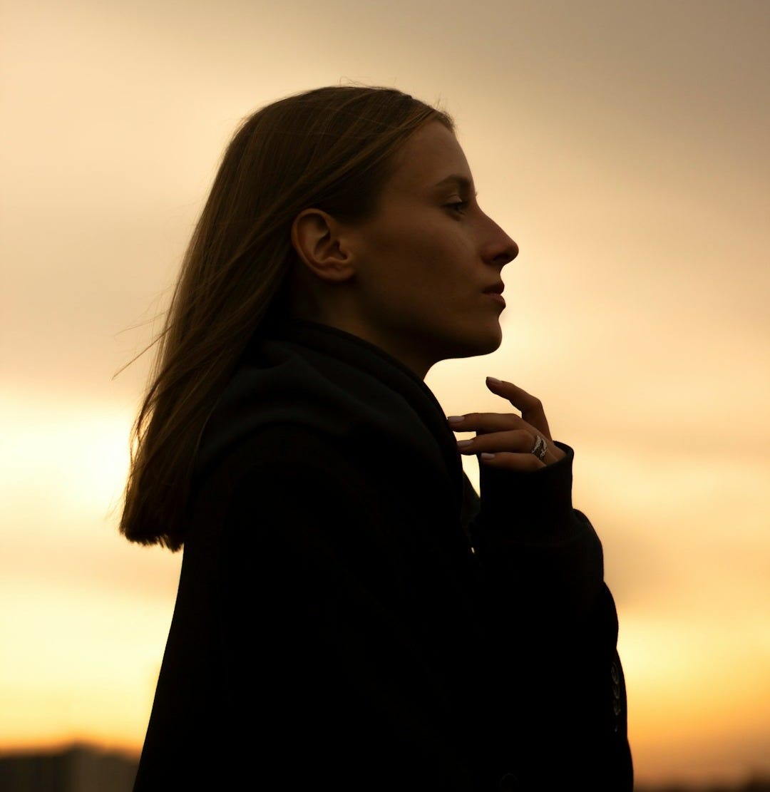 a woman standing in front of a sunset a woman standing in front of a sunset
