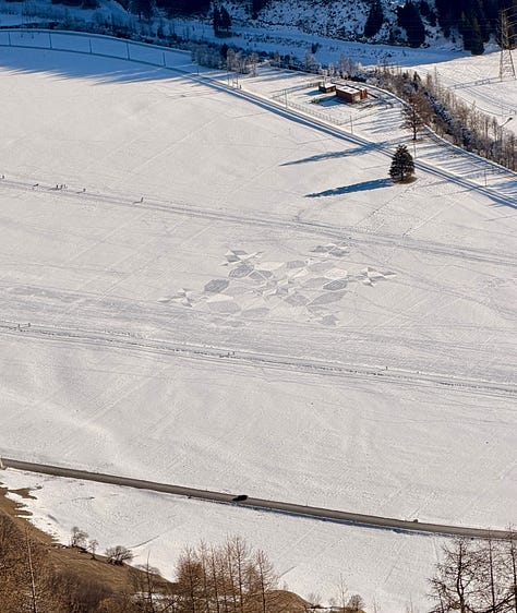 Left image, an elderly couple in a winter, alpine setting, high above a snow-covered valley floor smile for a selfie. Behind them, snow-capped mountain peaks; middle image, blackbirds riding the thermal above the Upper-Rhone Valley.; middle image, the top-right portion of a large wooden cross in a winter alpine setting. The cross perches over a snow-covered valley and mountain peaks opposite. A swarm of blackbirds ride a thermal.; right image, A snow-covered alpine valley floor from an elevate position. A metatrons cube has been raked into the snow using cross-hatching.