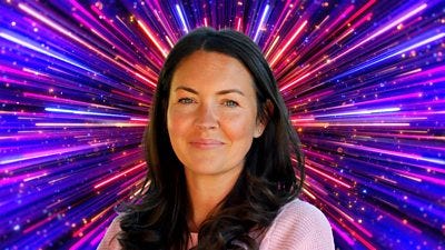 A woman with long dark hair smiles to camera, set against a glittering background with rays of red, pink, purple and blue light A woman with long dark hair smiles to camera, set against a glittering background with rays of red, pink, purple and blue light