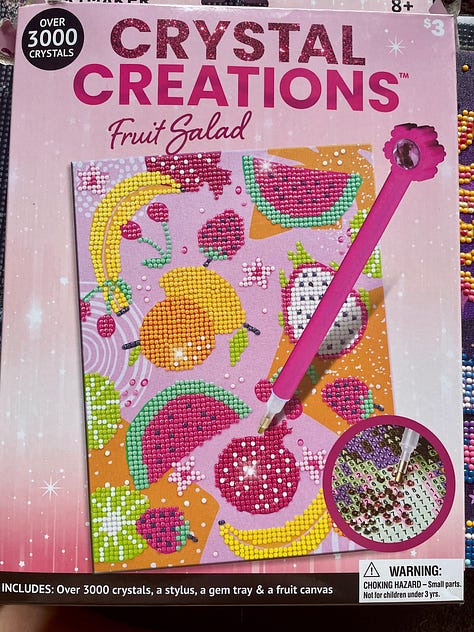 3 photos of 'diamond art' creations where small plastic gemstones in varying colours are slowly added to paper in a specific pattern. It is methodical and soothing but also fun and colourful art. The photos feature an irredescent fairy, a colourful moon and sun illustration with stars. planets and butterflies for decoration, plus a colourful fruit scene with watermelon, dragonfruit, cherries, bananas, oranges and strawberries, with the sticking pen tool in view.