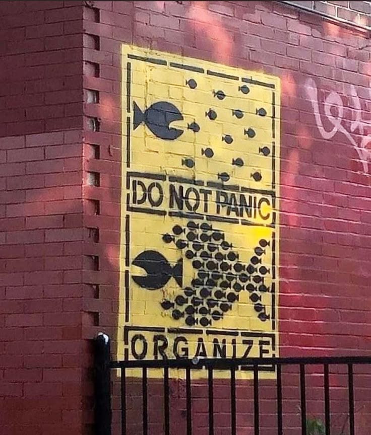 This may contain: a sign on the side of a brick building that says do not panic or organize