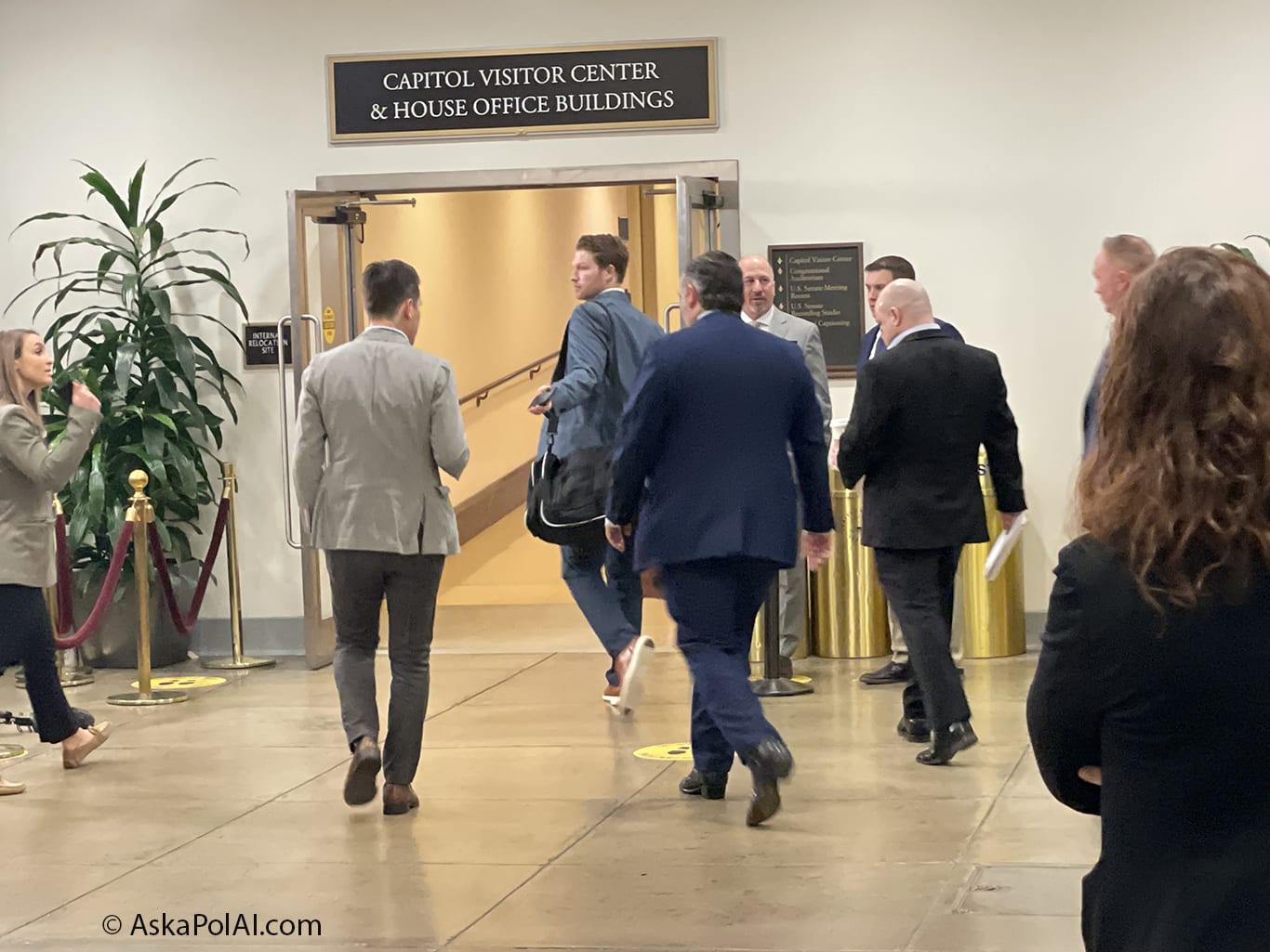 Men in suits walk towards a tunnel in an office building. © Ask a Pol AI Men in suits walk towards a tunnel in an office building. © Ask a Pol AI