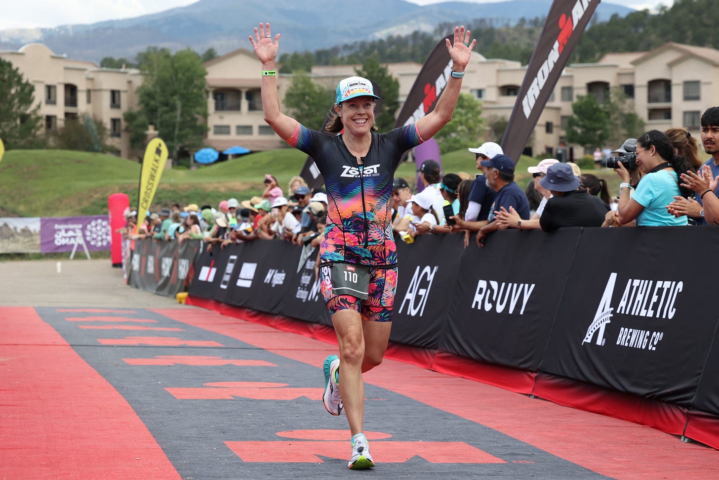 Jane Pilger running down the finishing chute arms up at the inaugural Ruidoso 70.3 ironman triathlon