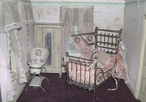 This may contain: a doll's bedroom with a baby crib, chair and dresser in it