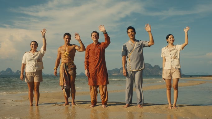 The staff of the White Lotus Thailand resort wave on the beach to incoming guests