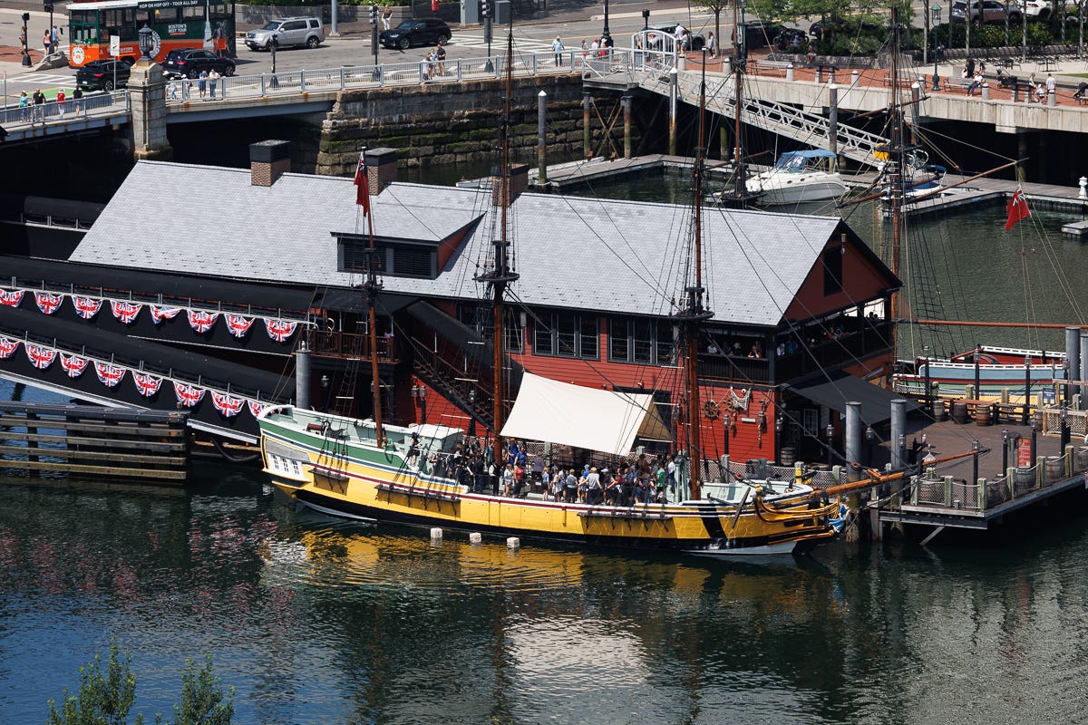 Colonial reenactment ship docked at Boston Tea Party Museum with crowd gathered on deck Colonial reenactment ship docked at Boston Tea Party Museum with crowd gathered on deck