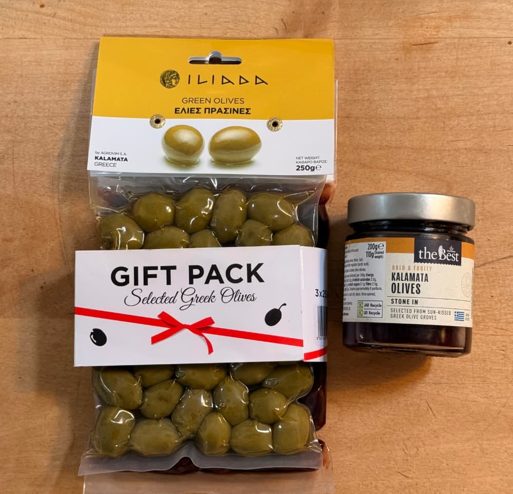 A packet of some olives next to a jar of some lesser olives.