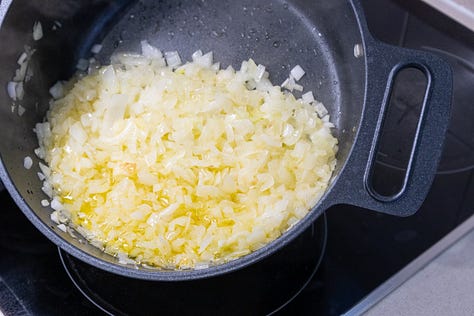 Olla con cebolla dorándose, añadiendo tomate y especias y luego el pollo
