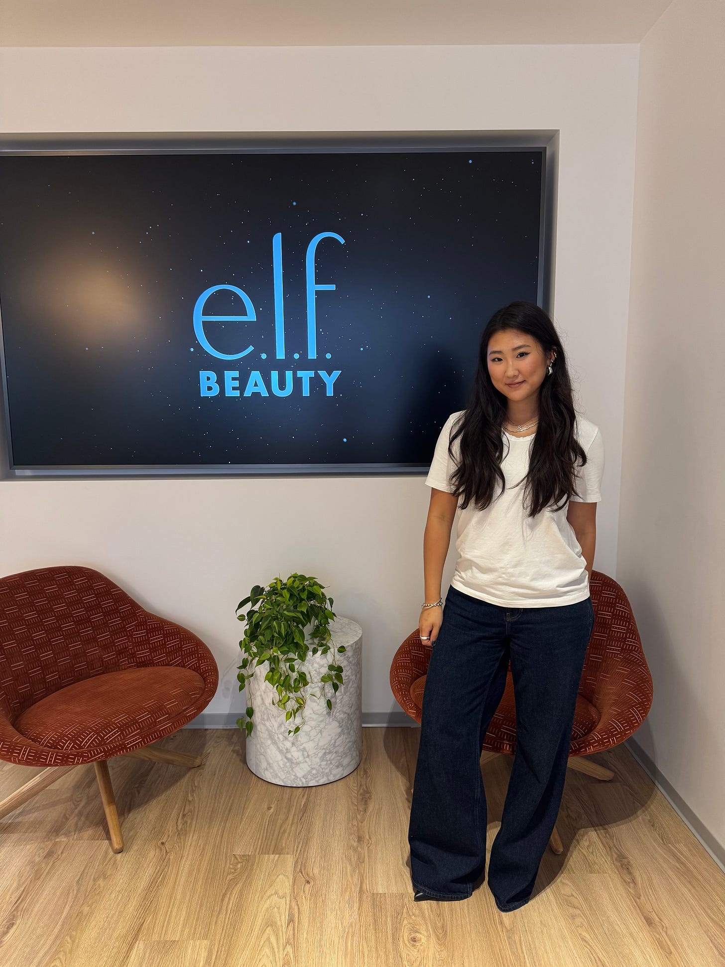 Katie standing in front of e.l.f. logo at the office.