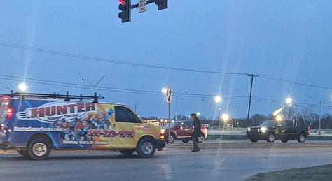 A van approaches a man crossing an intersection