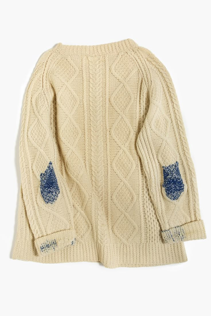 This may contain: a white sweater with blue patches on the sleeves