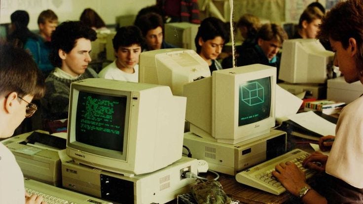 This may contain: there are many people sitting at computers in the room and one man is typing on his computer