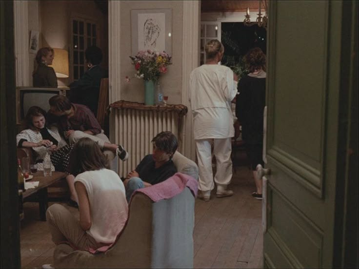 This may contain: a group of people sitting around in a living room