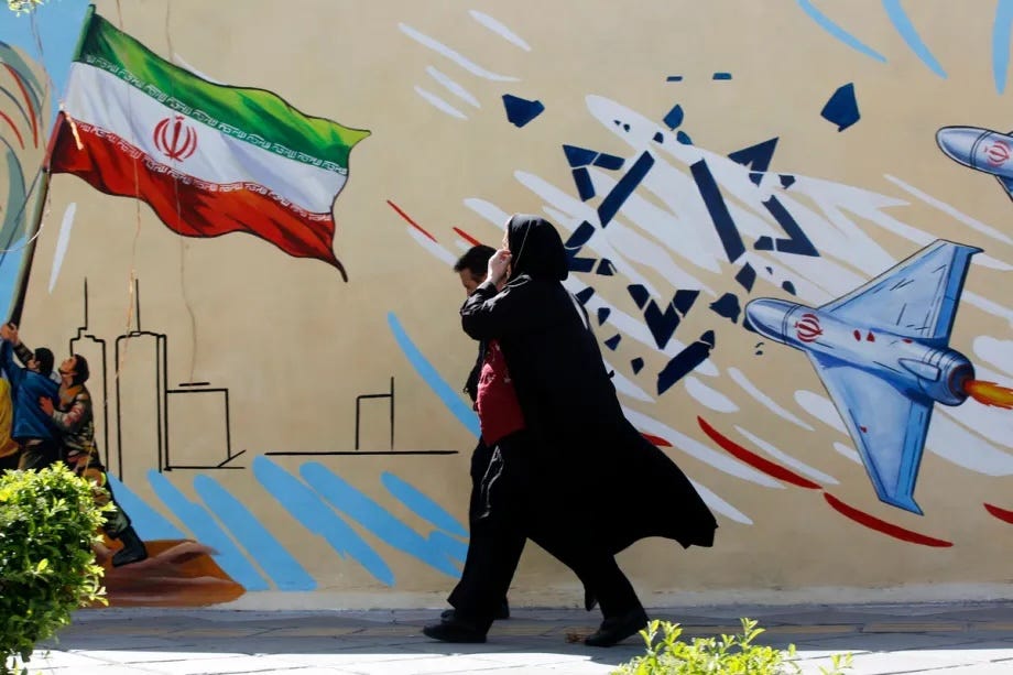 Residents walk past colorful wall paintings as daily life continues under the shadow of destruction following the U.S. and Israeli attacks on Tehran, Iran, on April 5, 2026.