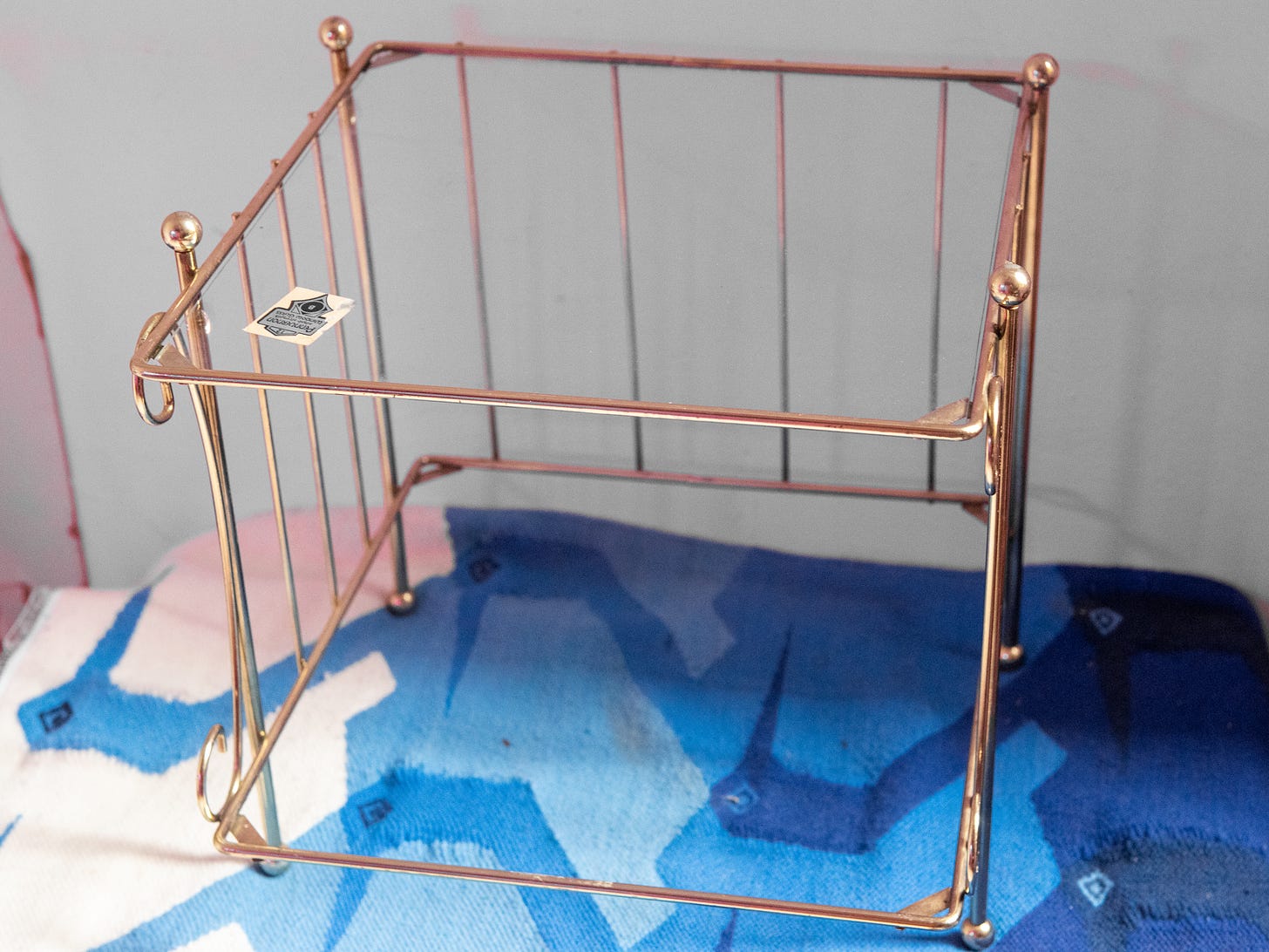 Image description: photo of brass cubical wire caddy with a glass tabletop. End image description.