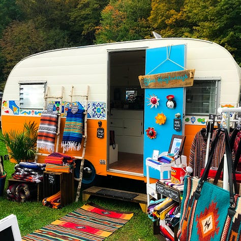 Vintage trailer painted orange turquoise and cream decorated with Mexican blankets and rugs