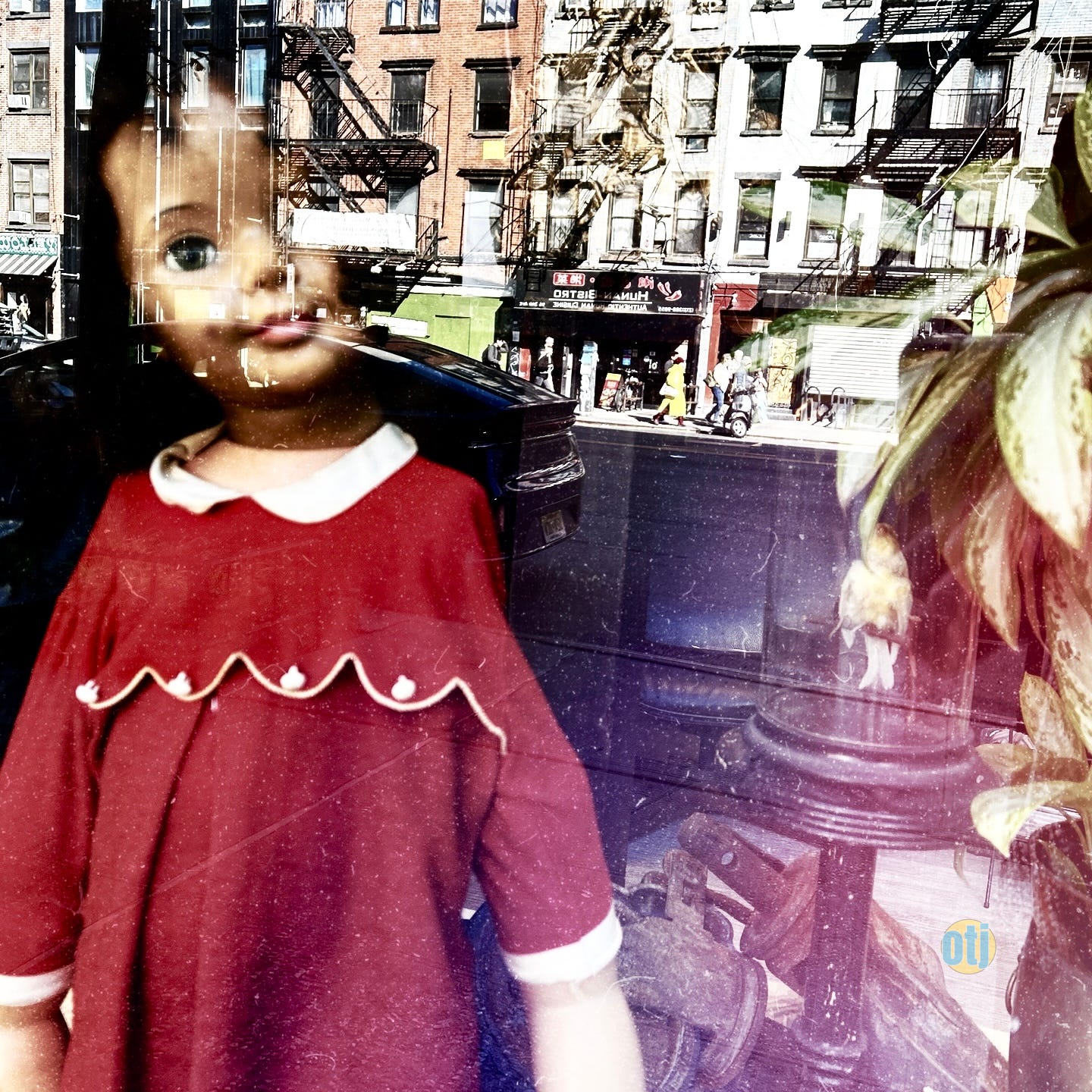 vintage doll in store window. Reflections of buildings in the glass.