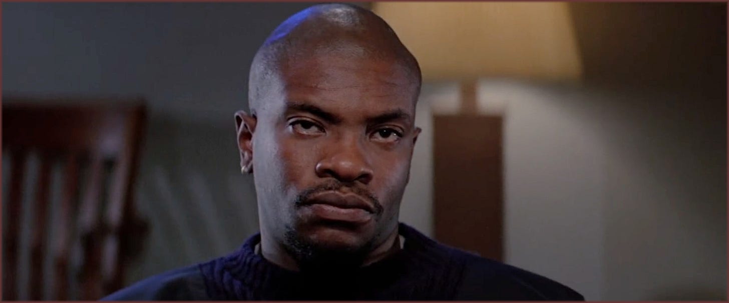 Close-up from The Thing (1982): Childs (Keith David) staring directly at camera before the blood test sequence, expression closed and unreadable.
