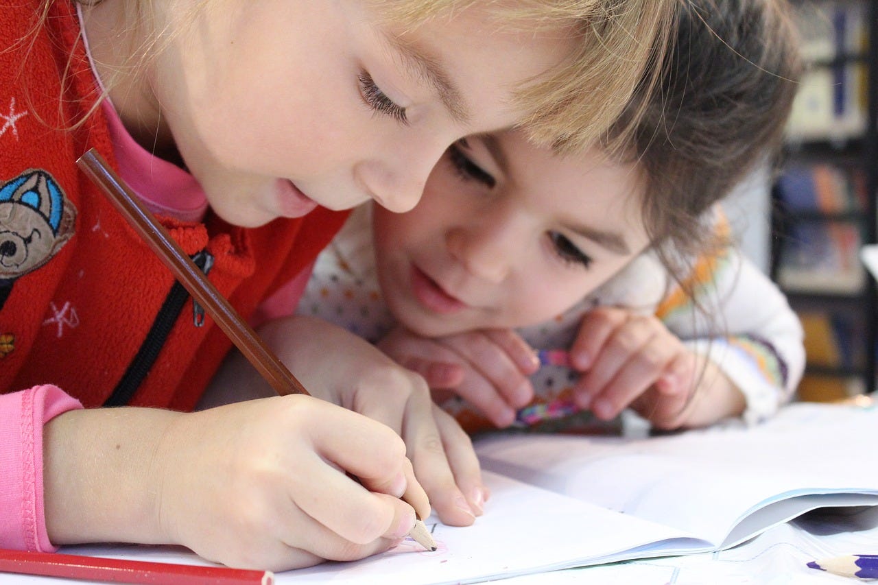 two young children look together at a book