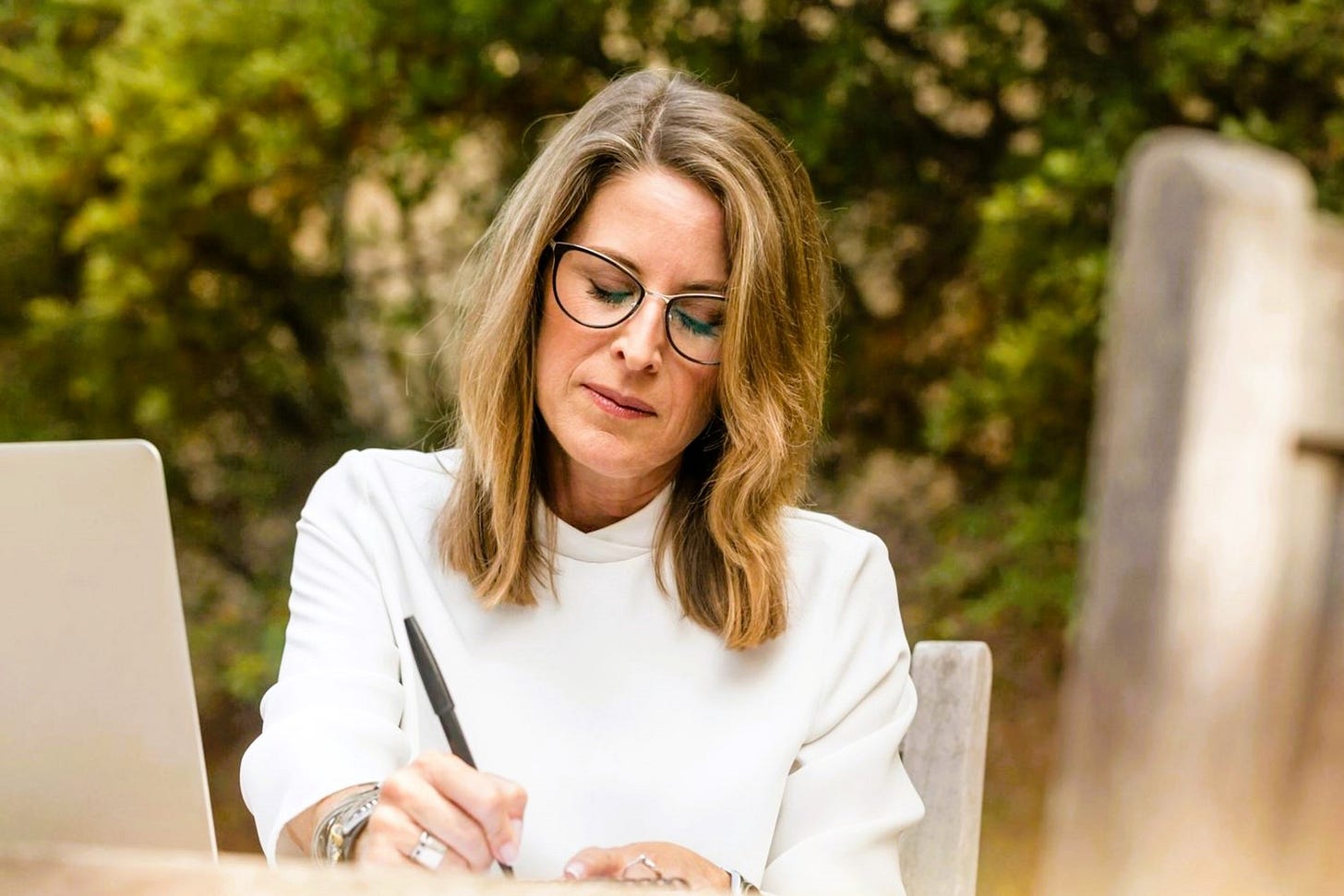 Woman in her 50s outside writing looking thoughtful Woman in her 50s outside writing looking thoughtful