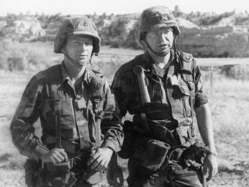 Black and white 1992 photo of Tim Walz and another soldier in camouflage uniforms, wearing helmets and other gear. Black and white 1992 photo of Tim Walz and another soldier in camouflage uniforms, wearing helmets and other gear.