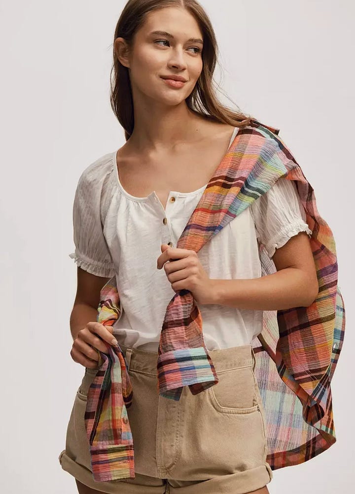 A purple floral dress, a woman wearing a white shirt, grey sneakers, and a white tote bag.