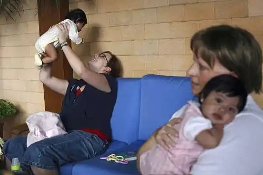 Dos mujeres estadounidenses sostienen a bebés guatemaltecos. Están jugando con ellos en el hotel Marriott de Ciudad de Guatemala. Las mujeres están allí para adoptar a estos niños y regresar con ellos a Estados Unidos.