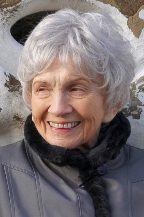 A torso-up picture of Alice Munro. She is smiling and looking to her right.