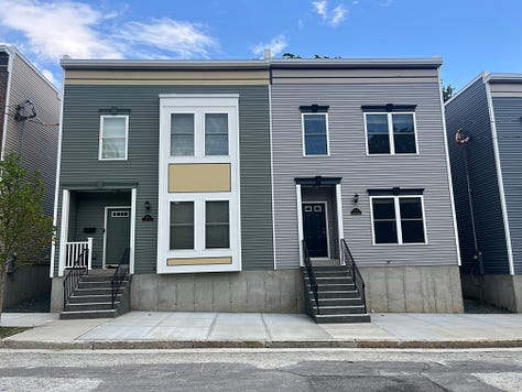 Exterior photos of new townhouses from the street and from the backyard. Several interior photos of a first floor with an open layout.