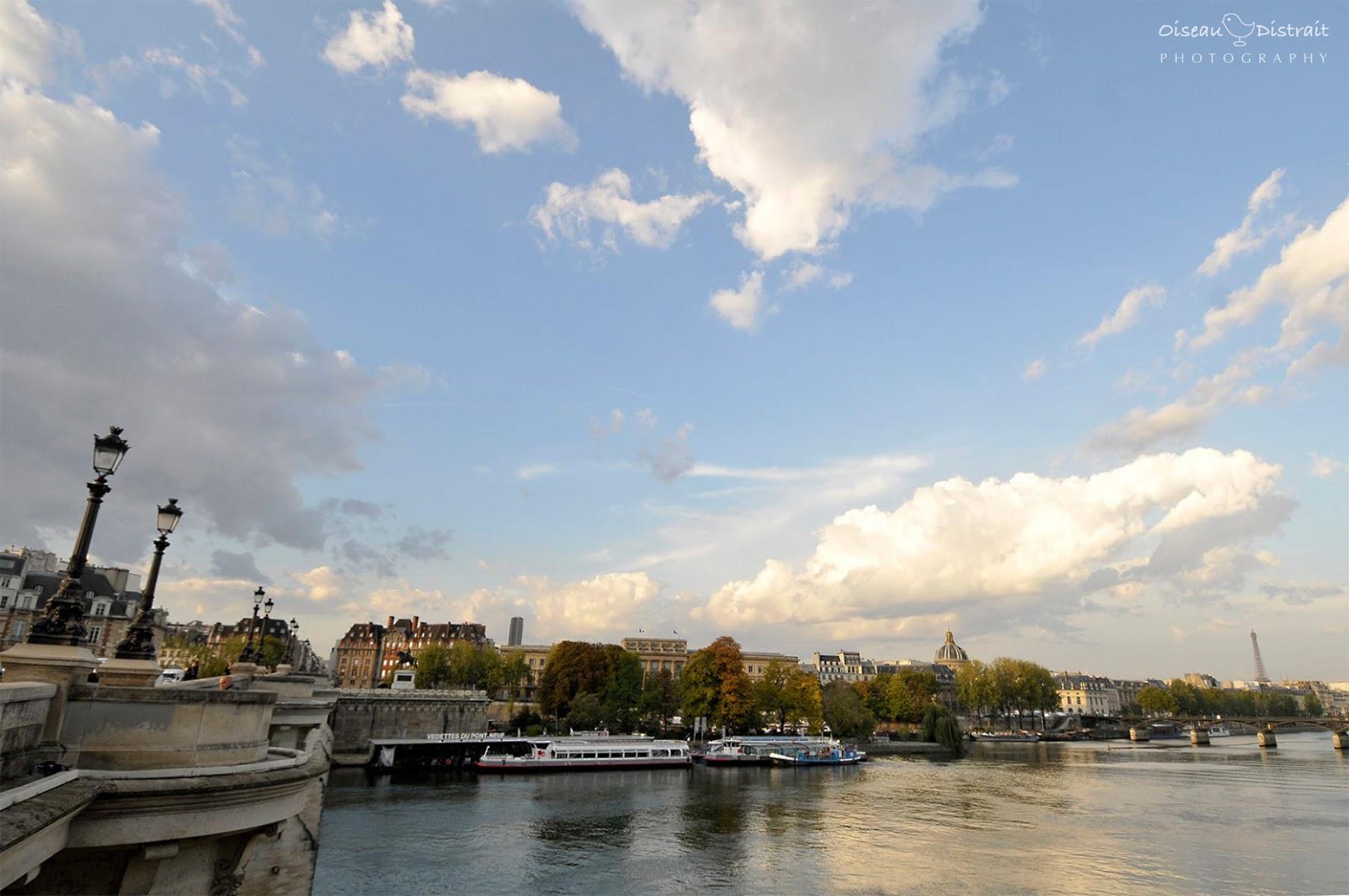 Wide angle of beautiful sunny day with white clouds on the bridge across the Seine in Paris. Wide angle of beautiful sunny day with white clouds on the bridge across the Seine in Paris.