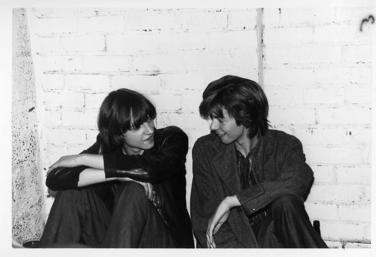 Mark E Smith and Ian McCulloch sitting on the floor chatting happily.