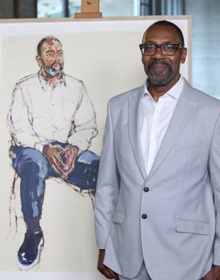 Lenny Henry in front of Morag Caister's portrait of him
