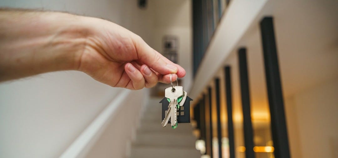 Here's a possible caption: keys being held in front of a staircase.