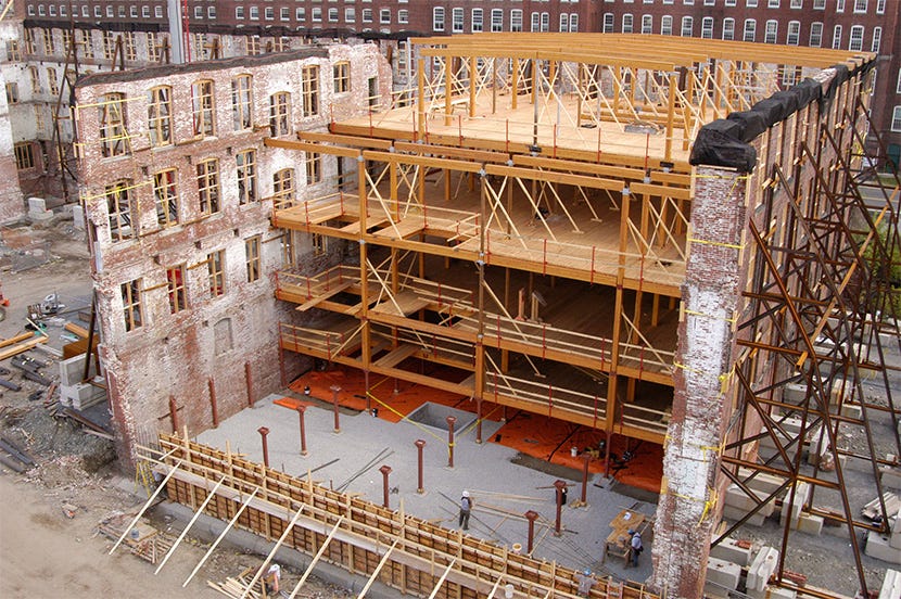 Shell of old brick industrial building full of new timber structures.