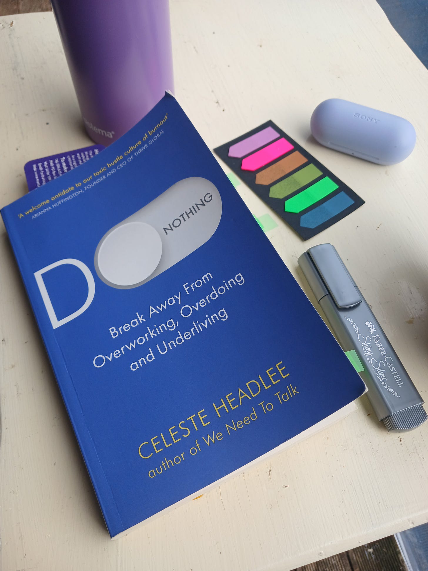 Image of the print book Do nothing by celeste headlee on a white table with highlights and drink bottle