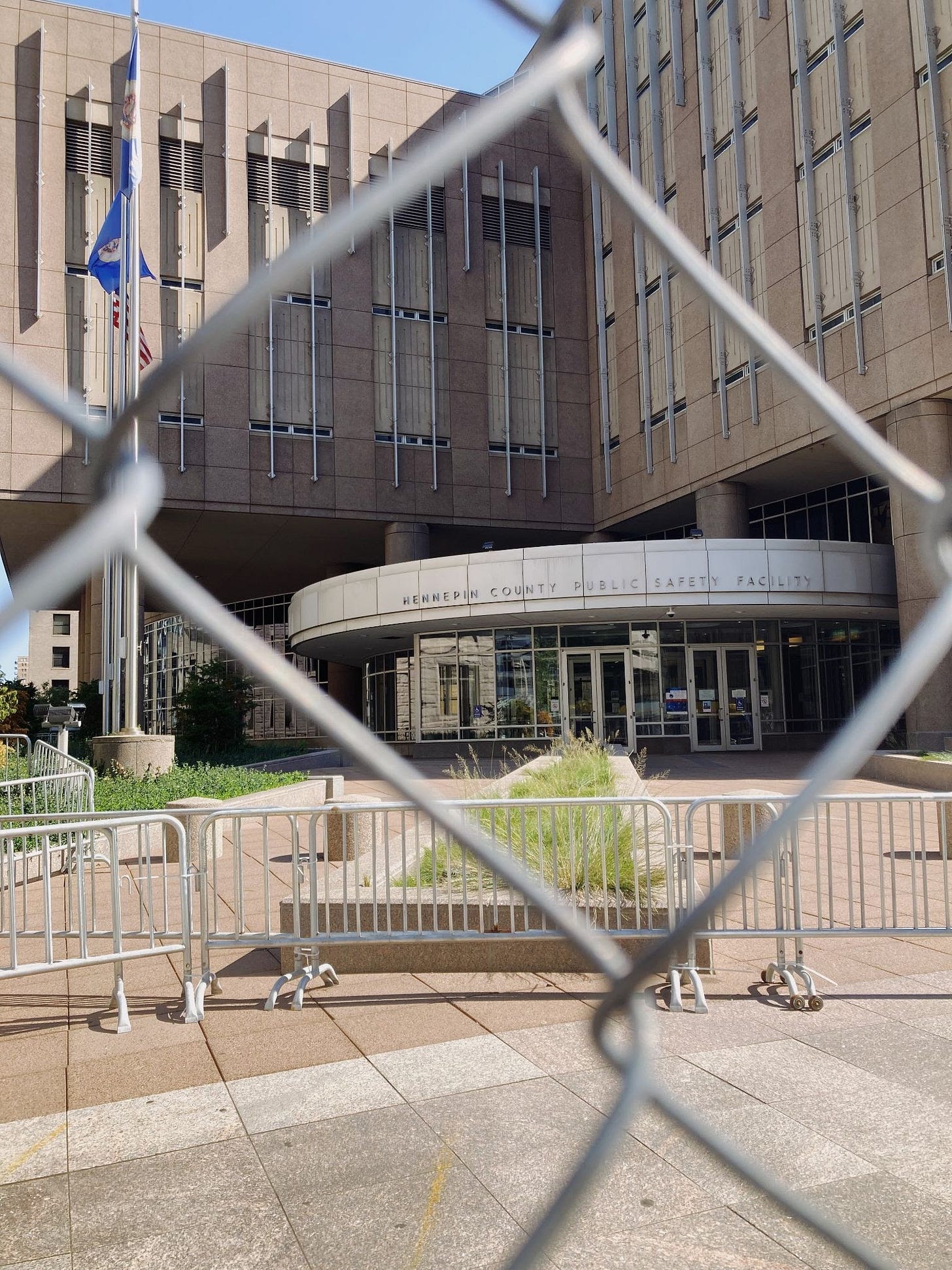 The entrance to the Hennepin County Public Safety facility, a beige brutalist building with skinny windows and metal bars