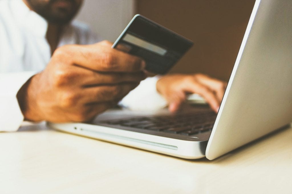 close up of man entering credit card information on laptop